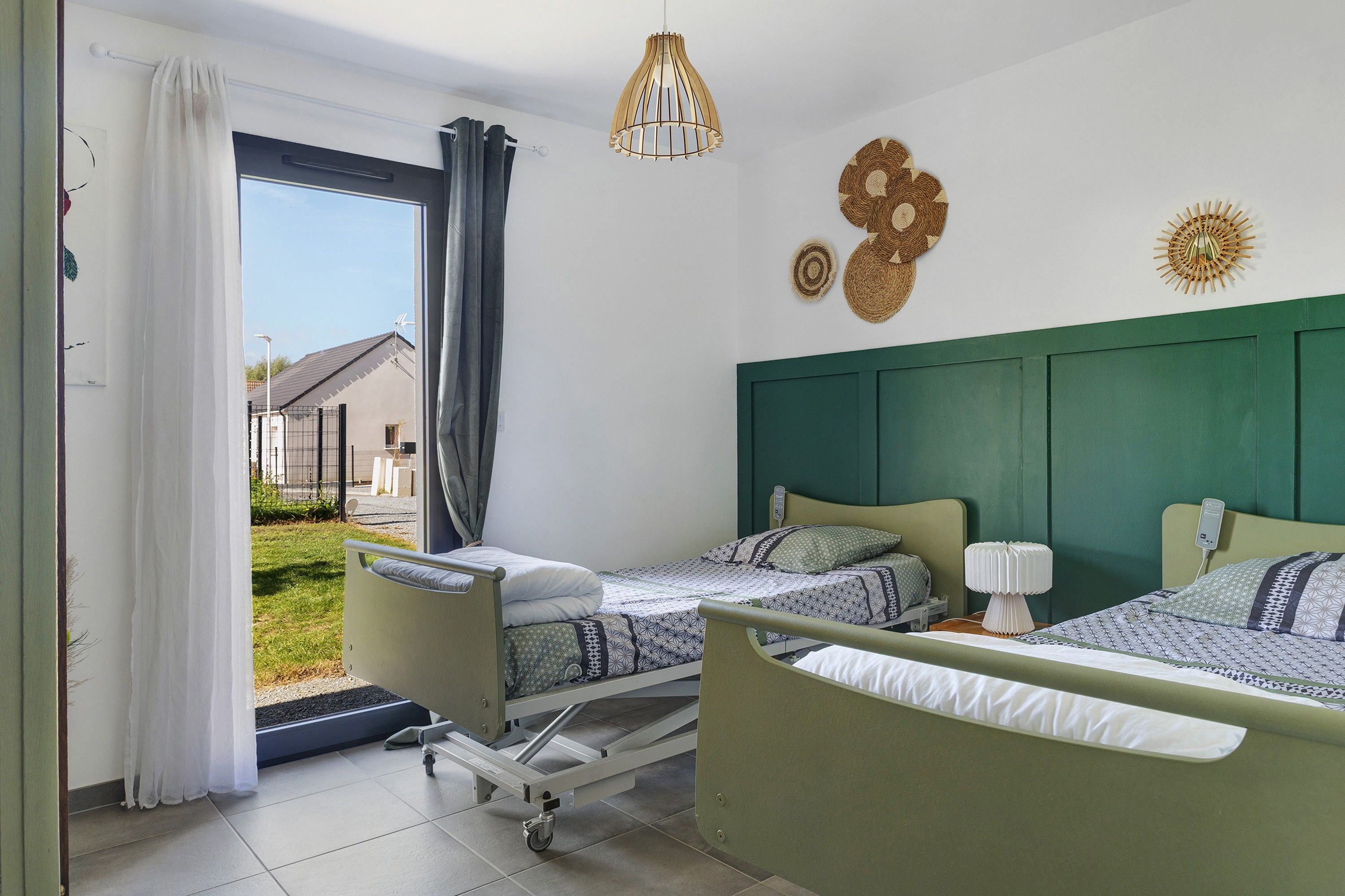 Una habitación con dos camas, una ventana con cortinas, una mesita de noche con lámpara y un adorno en la pared.