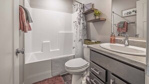 A modern bathroom with a shower, toilet, and vanity. - Family-Friendly 3BR | Dream Kids’ Room & Garage (Rapid City)