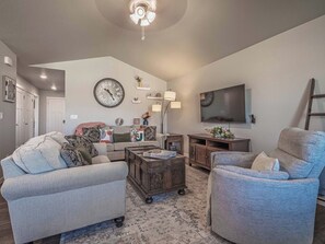Ein Wohnzimmer mit Sofa, Sessel, Couchtisch und Fernseher.