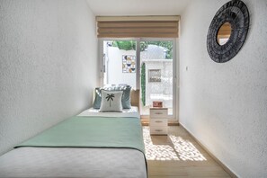 Un dormitorio con cama, cómoda, espejo y vistas al exterior.