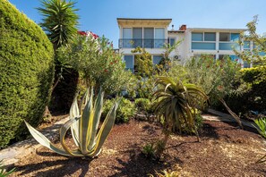 A landscaped garden with various plants and a building in the background. - Denize Sıfır Villa. Özel Plaj&Doğal Havuz.Bodrum (Milas)