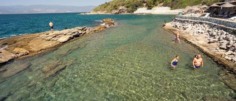 A coastal area with clear water, rocky shorelines, and buildings on a hillside.