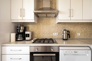 Een moderne keuken met roestvrijstalen apparatuur, waaronder een fornuis, koffiezetapparaat en waterkoker.