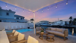 Un espace aménagé au bord de la piscine, avec des meubles d’extérieur, une vue sur le port de plaisance et des guirlandes lumineuses.