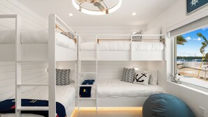 Une chambre avec des lits superposés, une vue sur la mer, un ventilateur de plafond et une fenêtre donnant sur les bateaux.