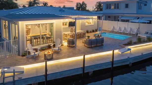 Une maison moderne dotée d’une piscine, d’un espace salon extérieur et d’une terrasse bien éclairée.