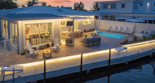 Uma casa moderna com piscina, área de estar externa e um pátio bem iluminado.