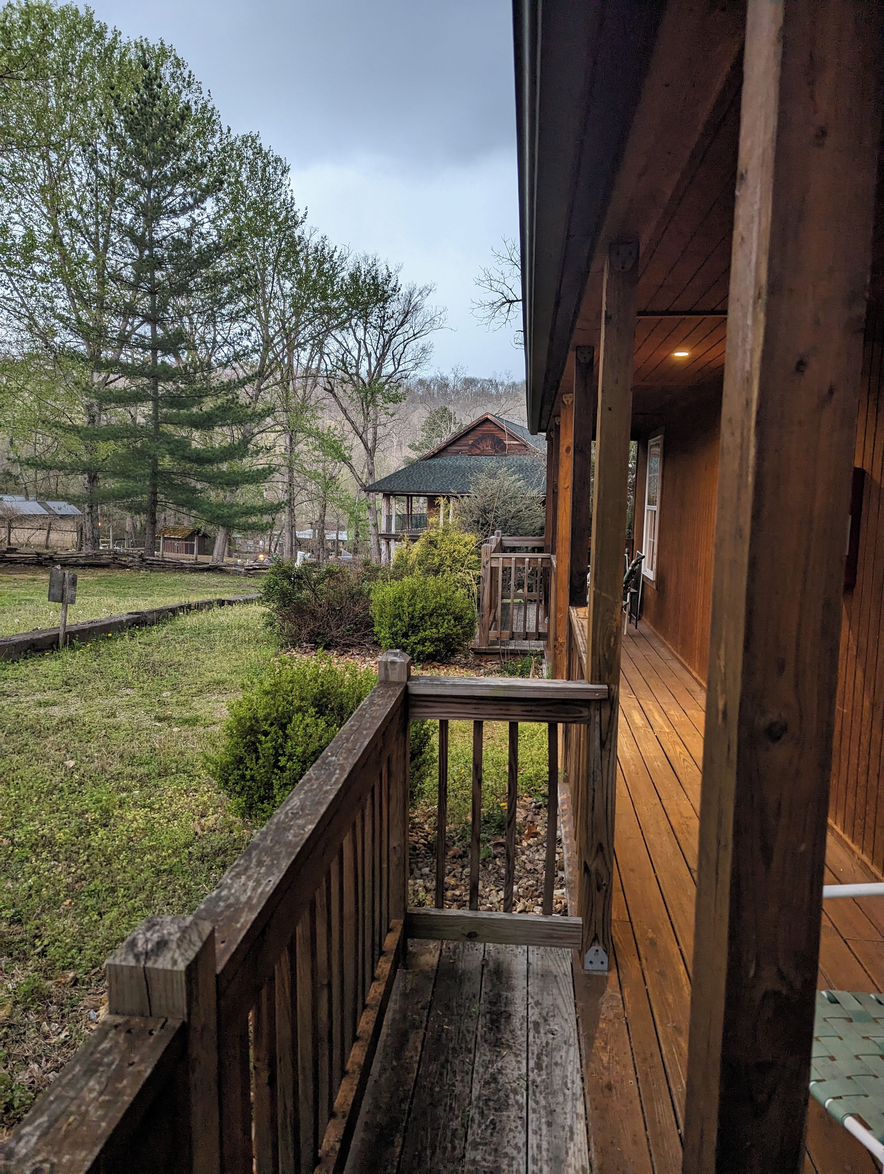 A wooden deck with a railing, leading to a building with a porch.