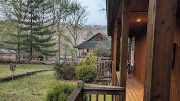 A wooden deck with a railing, leading to a building with a porch.