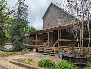 Un bâtiment rustique doté d’un porche, d’un escalier en bois et d’une enseigne indiquant « DAWT MILL ».