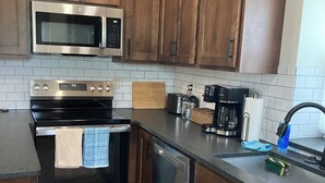 Una cucina con mobili in legno, elettrodomestici in acciaio inossidabile e zoccolo a mosaico.