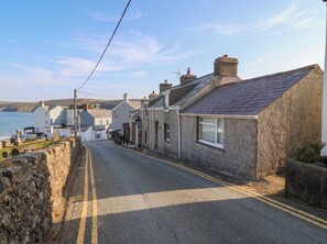 A coastal road with stone houses, a clear sky, and the sea in the background. - 5 Bryn Llan (Pwllheli)