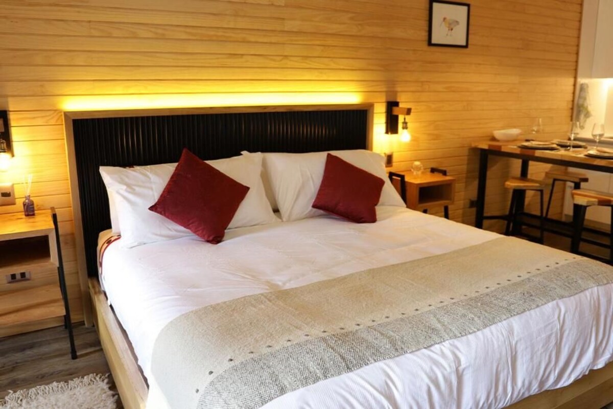 Ein Hotelzimmer mit einem großen Bett, zwei Nachttischen, einem Schreibtisch und einem Stuhl.