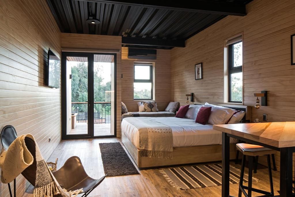 Un dormitorio con cama, escritorio, silla y un amplio ventanal.