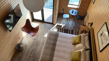 Una habitación con cama, una silla, una mesita y una ventana.