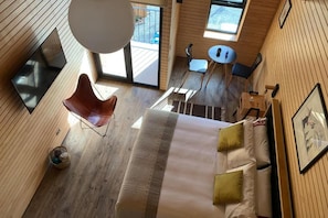 Una habitación con cama, una silla, una mesita y una ventana.