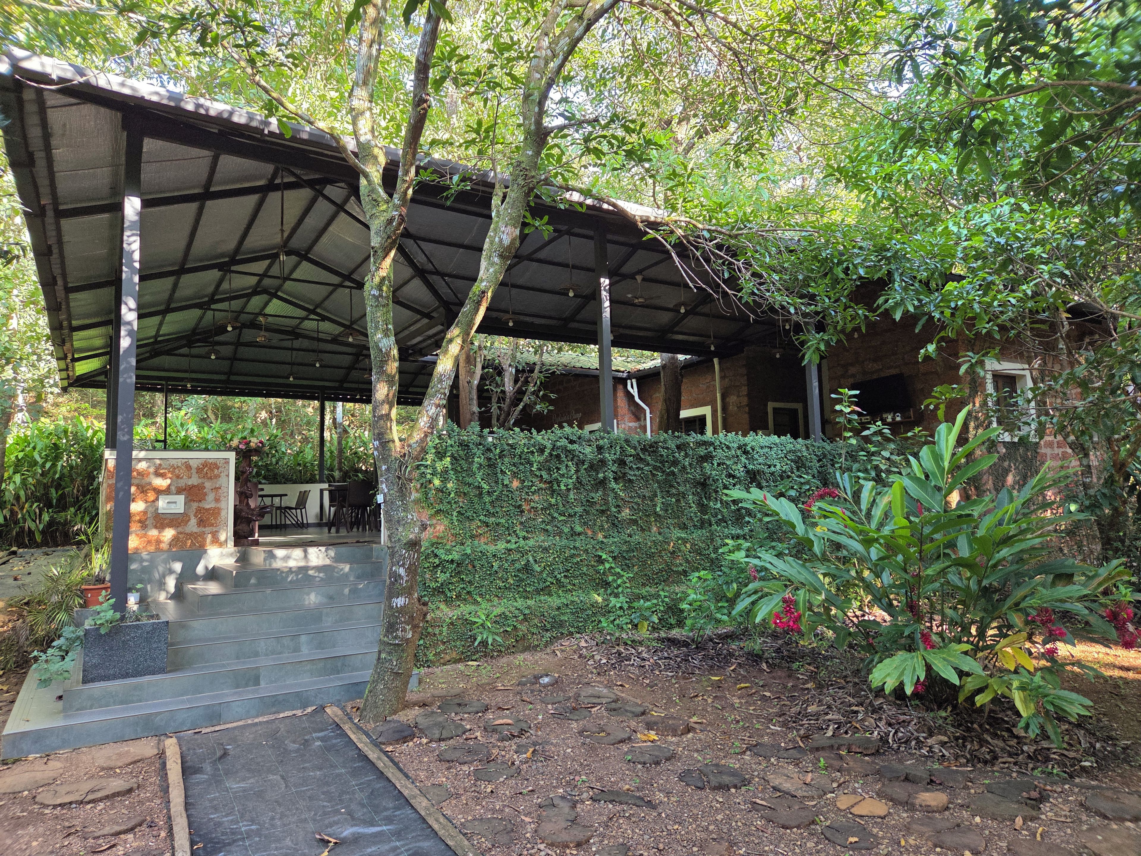 A covered outdoor area with a stone bench, a small table, and a potted plant.