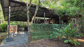 A covered outdoor area with a stone bench, a small table, and a potted plant.