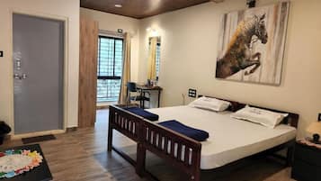 A hotel room with a bed, a bench, a table with a doily, and a painting on the wall.