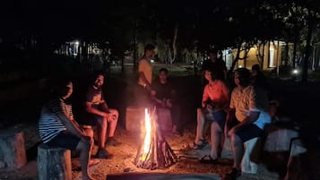 A group of people sitting around a campfire at night.