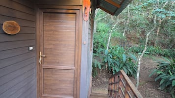 Una puerta de madera con un picaporte de metal, un felpudo y un letrero de madera en la pared.