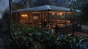 Un edificio de estilo rústico tipo cabaña, con un letrero de neón, fachada de madera y un área de estar al aire libre cubierta.