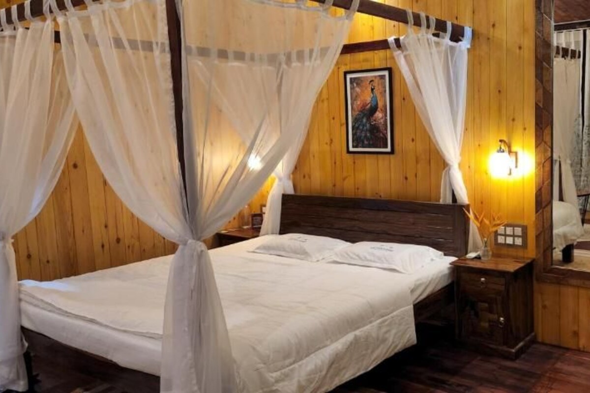 A bed with a canopy, a bedside table, a wall-mounted light, and a mirror.