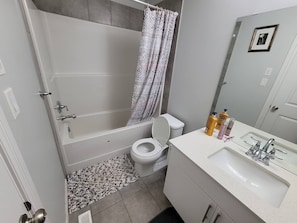 Een badkamer met een badkuip, toilet, wastafel en douchegordijn.