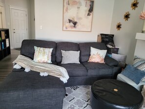 A living room with a grey sofa, patterned throw, and decorative pillows. - Room-charming and Cozy Home (Edmonton)