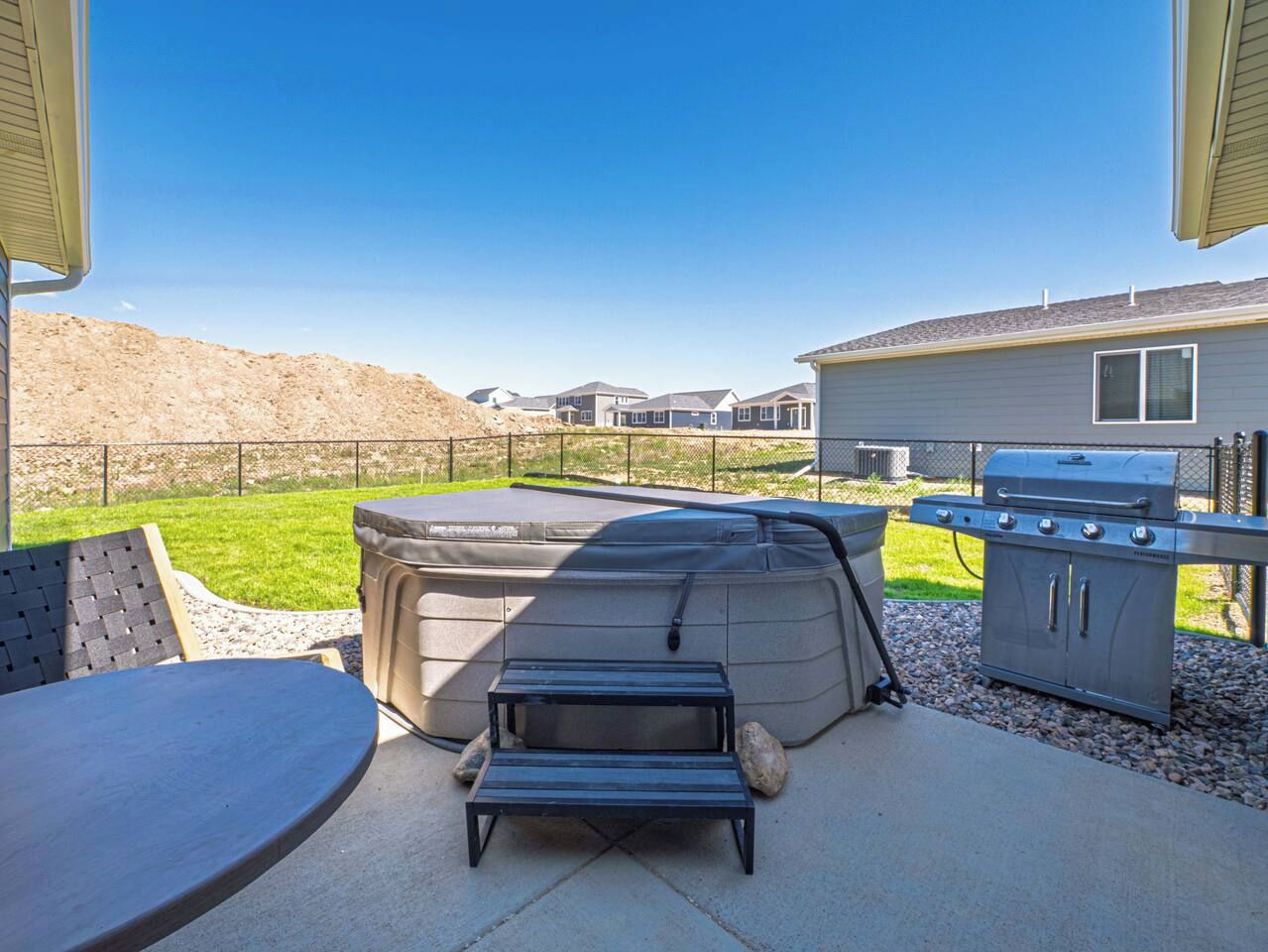 Une terrasse extérieure avec un jacuzzi, un barbecue et un espace salon.