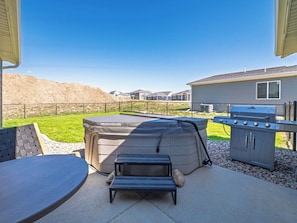 Un patio al aire libre con un jacuzzi, una parrilla y una zona de estar.