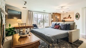 Un dormitorio moderno con cama, escritorio, televisor y zona de comedor.