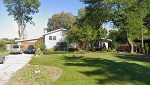 Una propiedad residencial con una casa blanca, un camino de entrada y un césped bien cuidado.