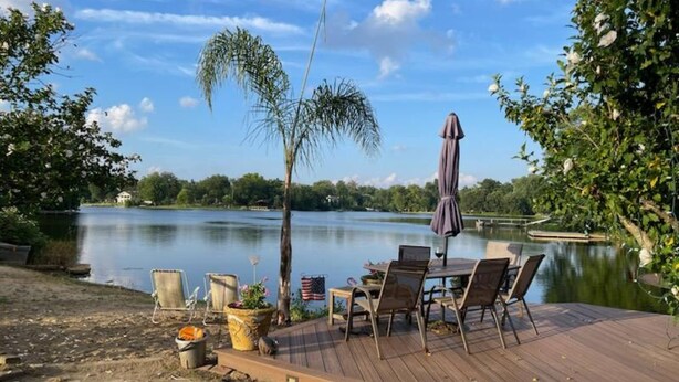 Una terraza de madera con muebles de exterior, una pequeña mesa y una planta en maceta.