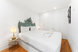 A hotel room with a bed, two bedside lamps, a wardrobe, and a small round table. - GuestReady - Charming Duplex in Porto's Heart (Porto)