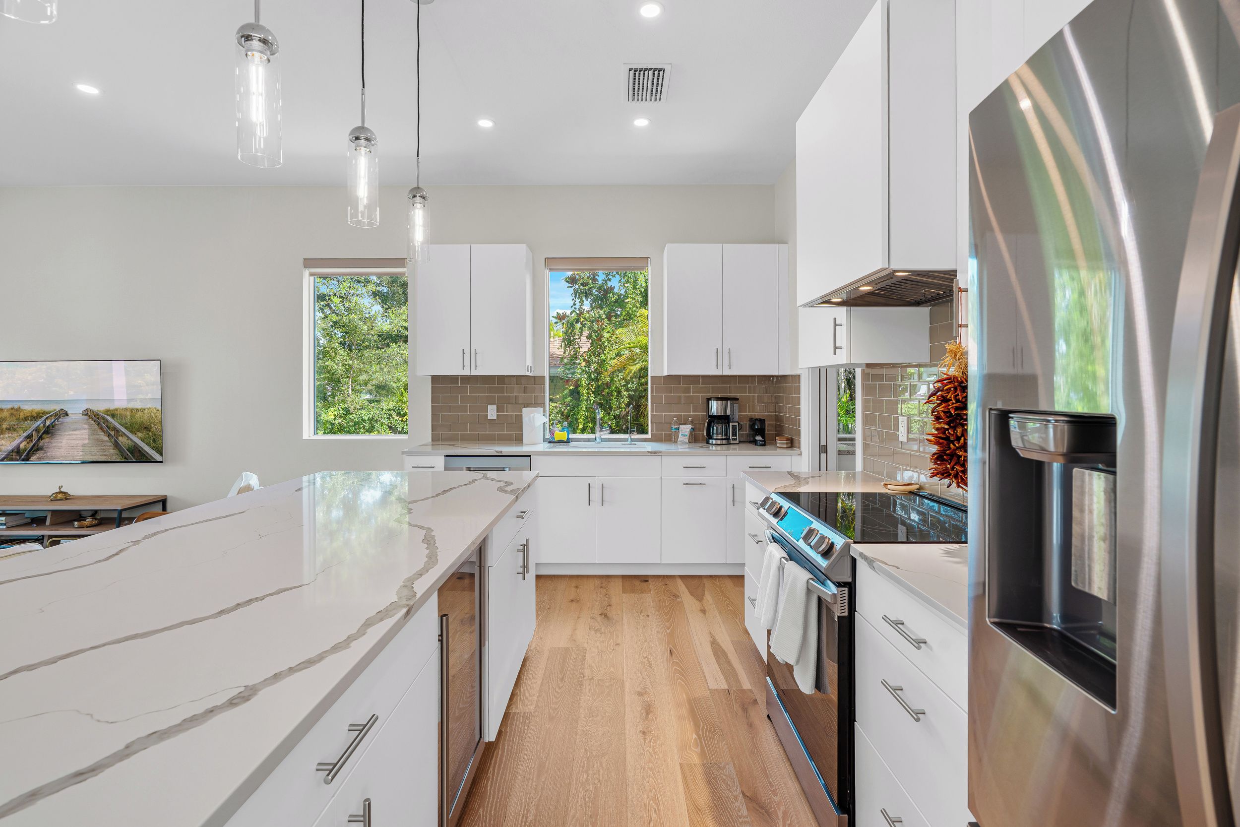 A modern kitchen with white cabinets, a marble countertop, and stainless steel appliances.