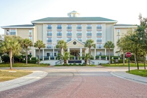 Un hotel grande con entrada central, varios pisos y una señal de stop al frente.