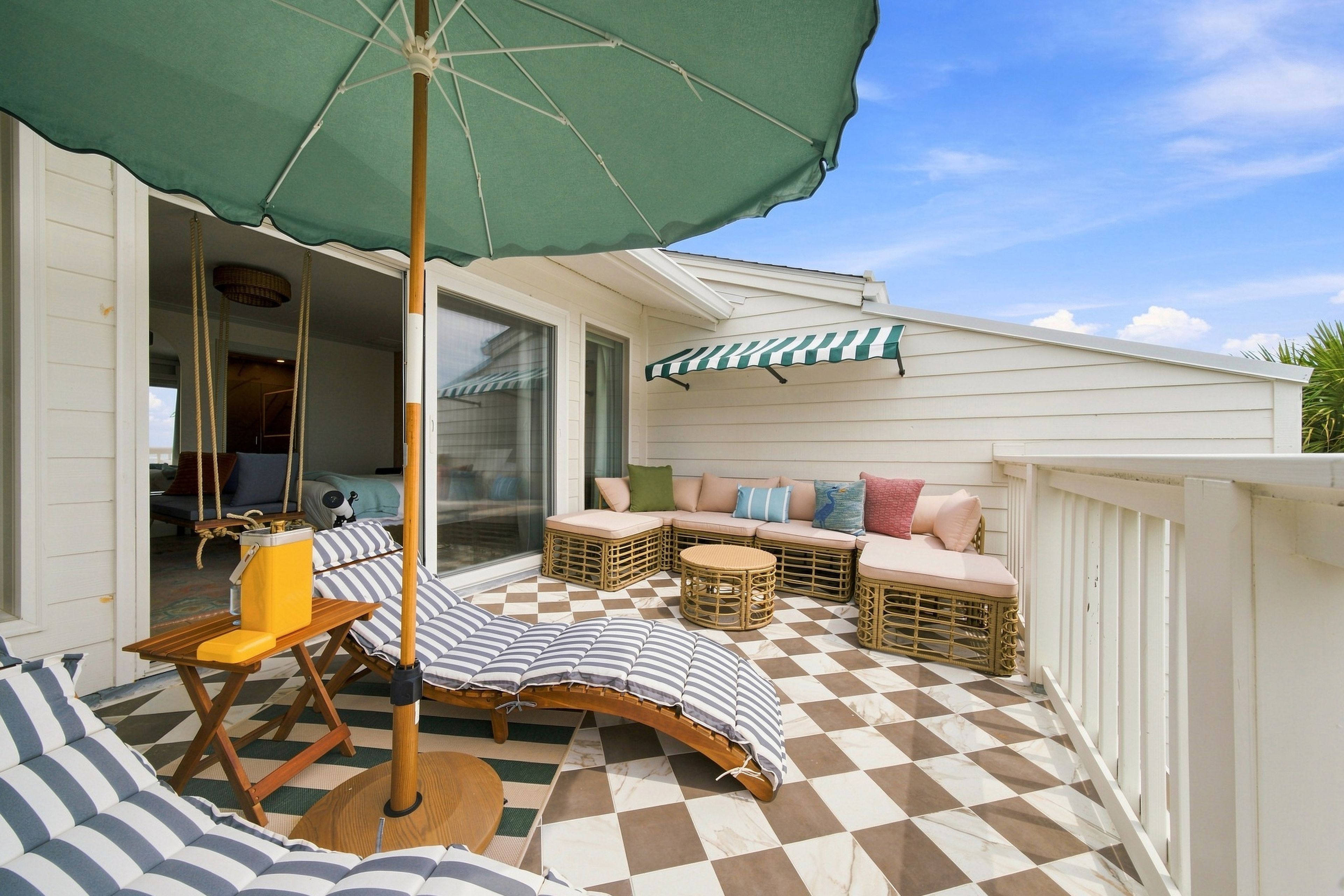 A covered outdoor seating area with a checkered floor, a table, and a chair.
