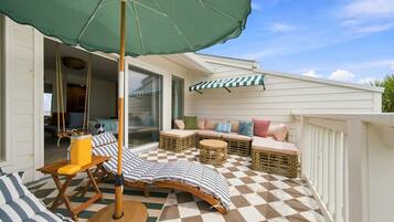 A covered outdoor seating area with a checkered floor, a table, and a chair.