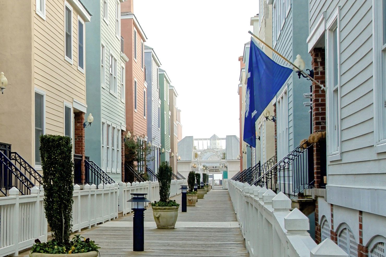 A row of colorful townhouses with a wooden boardwalk between them.