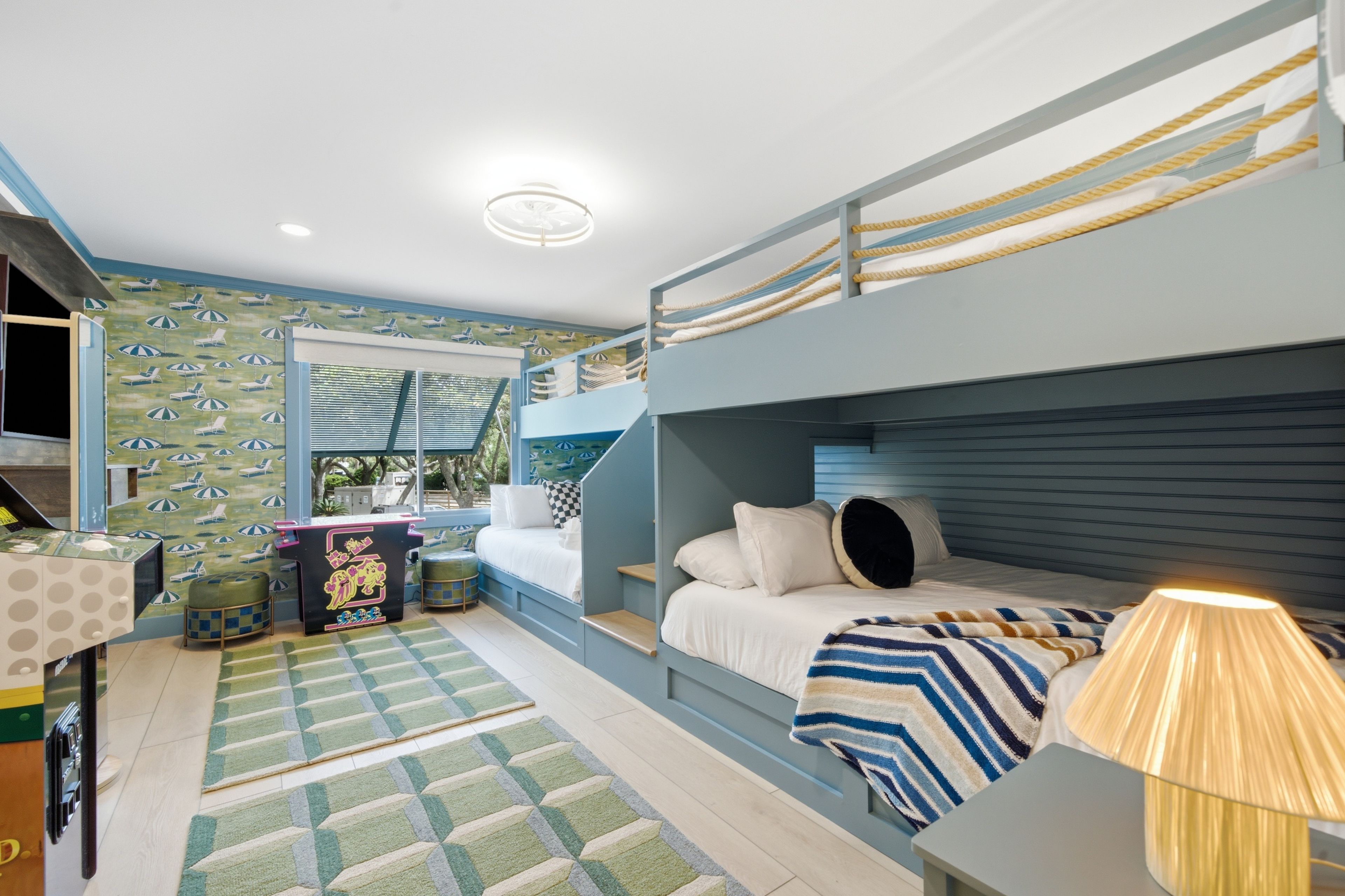 A bunk bed room with a desk, a chair, and a lamp.