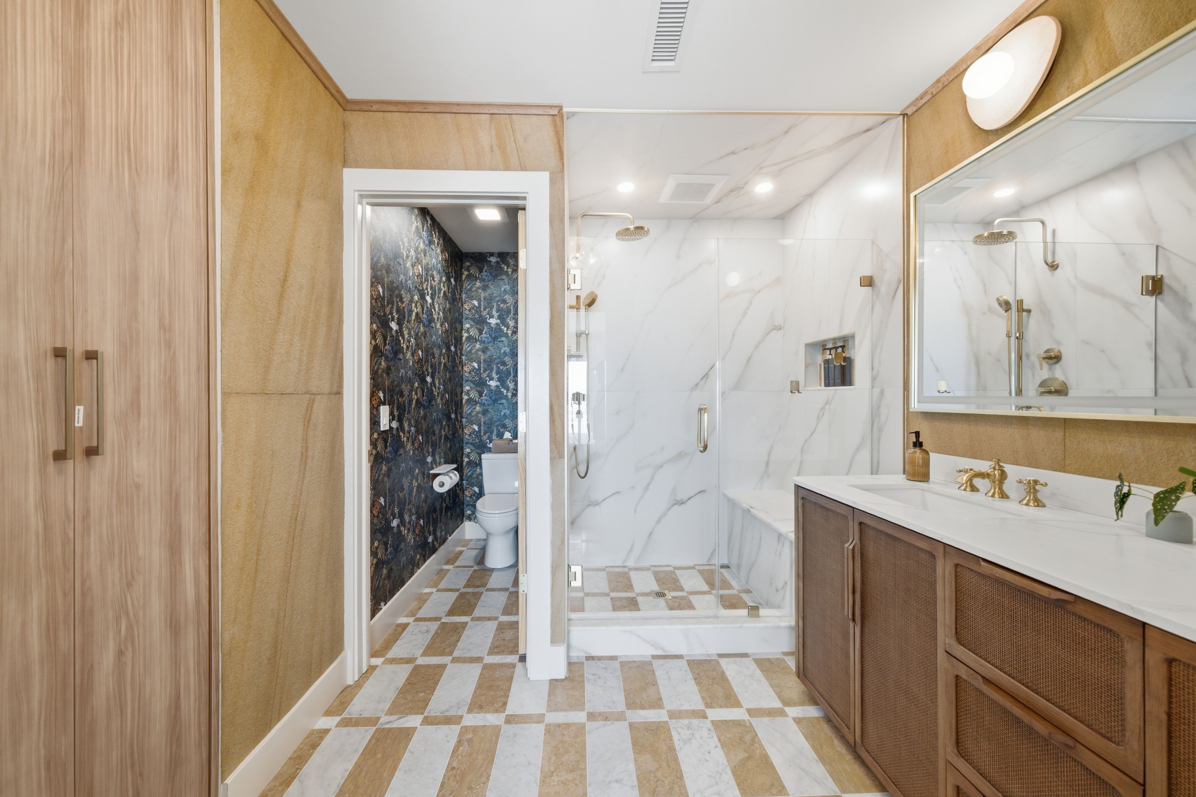 A bathroom with a checkered floor, a shower, a toilet, and a vanity with a mirror.