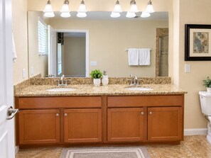 A bathroom with a double vanity, a large mirror, and a shower visible through the door. - 6BR Family Vacation Home Paradise Palms Private Pool Near Disney (Kissimmee)