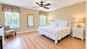 A bedroom with a bed, nightstands, a chair, a ceiling fan, and windows with blinds. - 6BR Family Vacation Home Paradise Palms Private Pool Near Disney (Kissimmee)