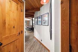 A wooden door leading to a hallway with framed pictures on the wall and a visible room in the background. - Petros Place Ptarmigan Village Hot Tub Pool (Whitefish)