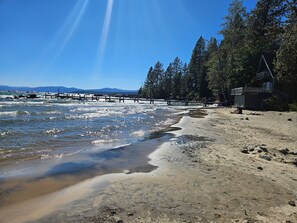 A beach with a wooden walkway, clear skies, and distant mountains.
