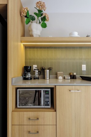 Eine moderne Küche mit integriertem Mikrowellenherd, Kaffeemaschine und einer dekorativen Vase mit Blumen.