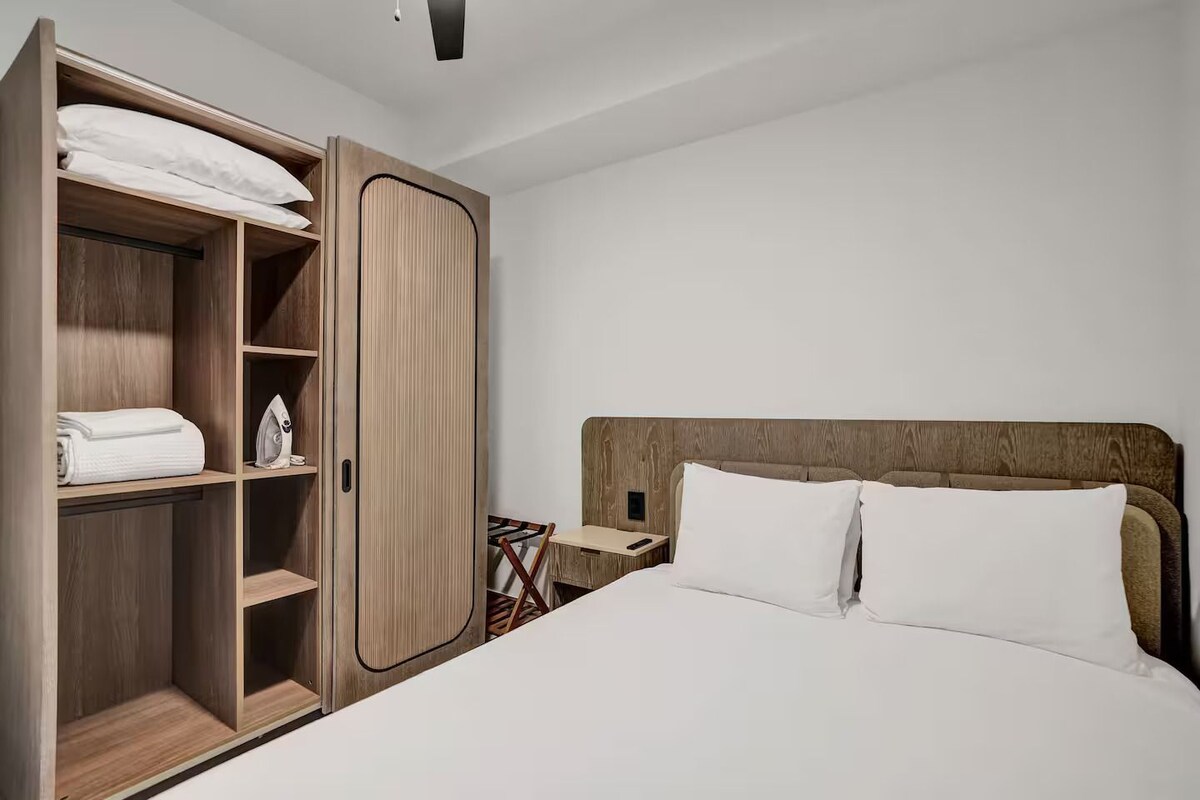 A bedroom with a bed, a wardrobe, and a nightstand.