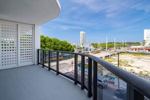 Varanda com vista para uma rua movimentada, uma placa de pare e um edifício ao fundo.