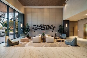 A modern lobby with a seating area, a wall with decorative elements, and a large window. - 72 Park by Mia Casa (Miami Beach)